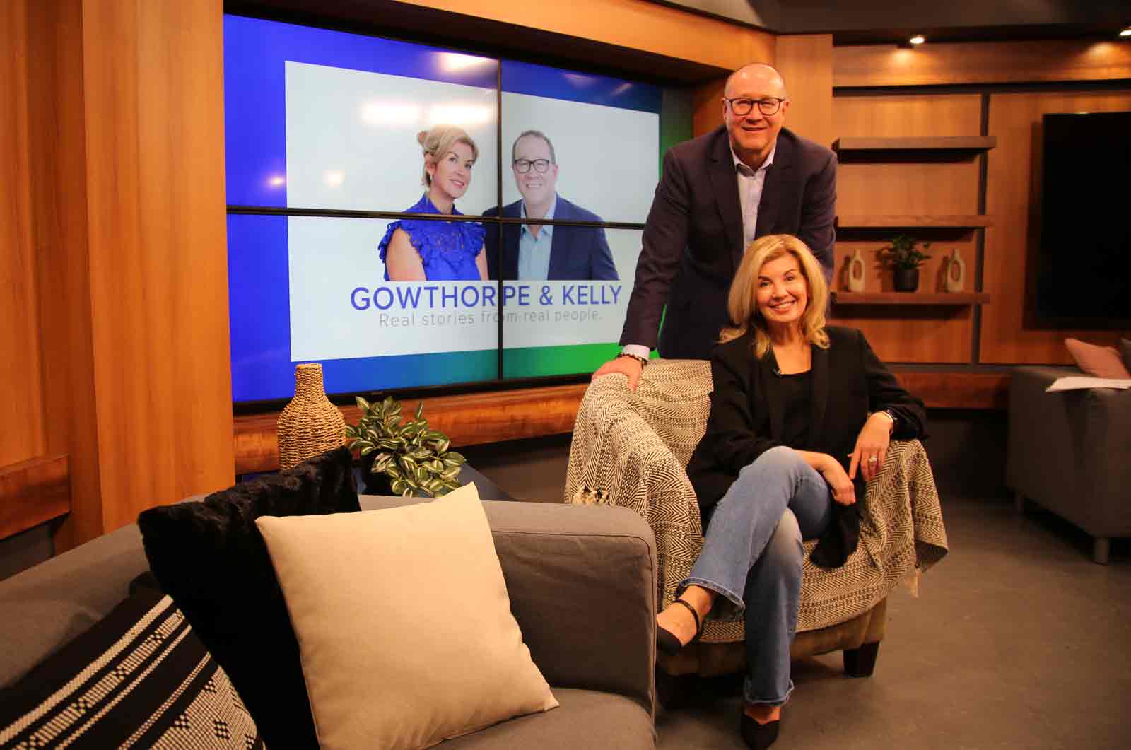 Speaker seated in a studio chair with co-host standing beside her on a professional talk show set, with the Gowthorpe & Kelly logo displayed on screens behind them.